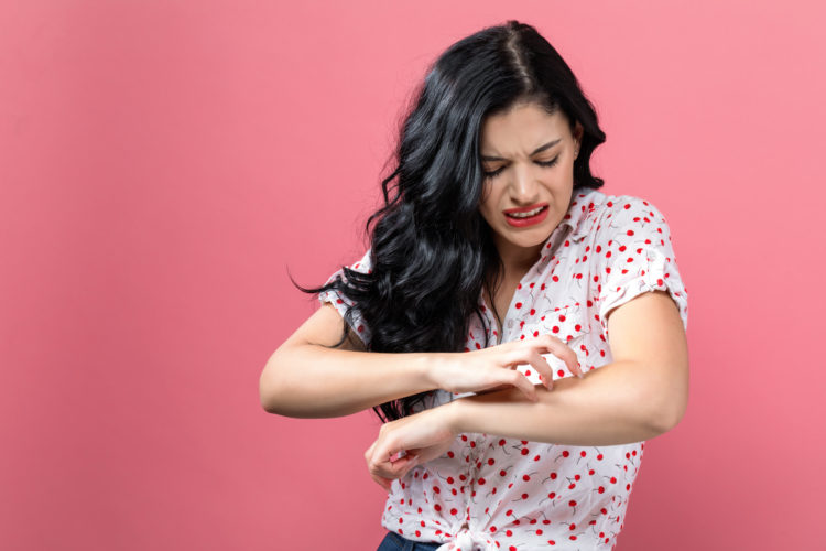 Young woman scratching her itchy arm. Skin problem.