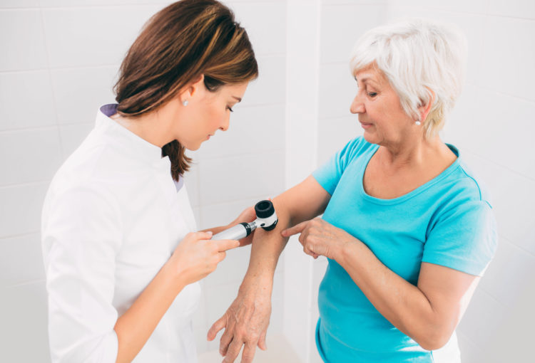 Doctor examining patient skin moles with dermoscope