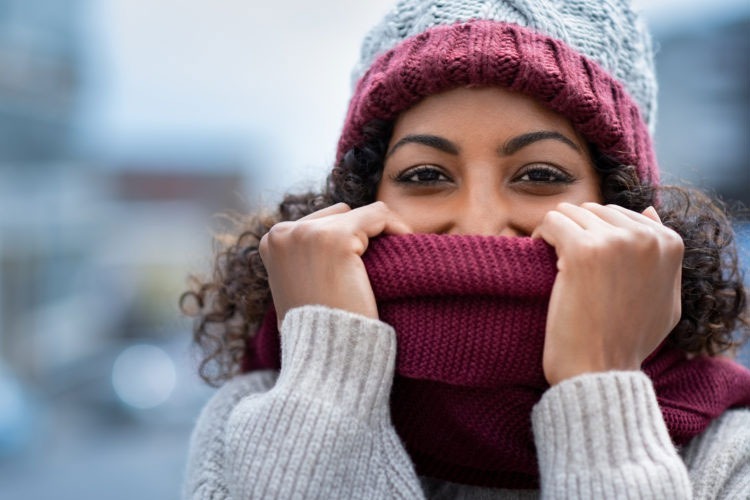 Beautiful woman hiding face in woolen scarf