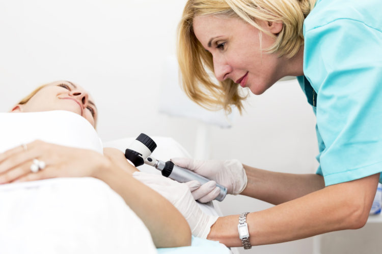 Woman undergoing medical exam using dermoscope
