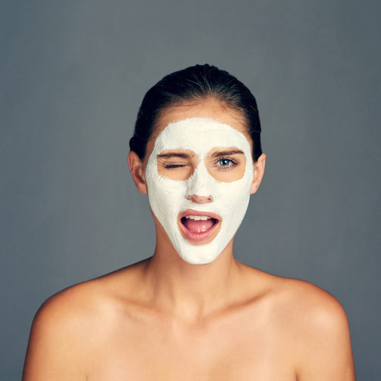 Studio shot of a young woman wearing a face mask against a grey background