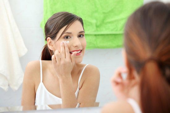 Woman applying cream on her face