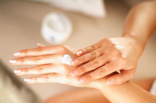 Beautiful woman applying sunscreen cream on her hand