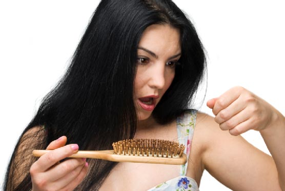 Woman losing hair on hairbrush