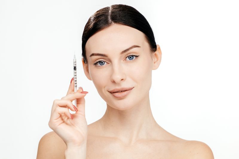 A woman holding a syringe for Botox near her face by Swinyer Woseth Dermatology